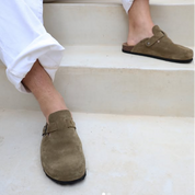 Man wearing green suede clogs on a white staircase